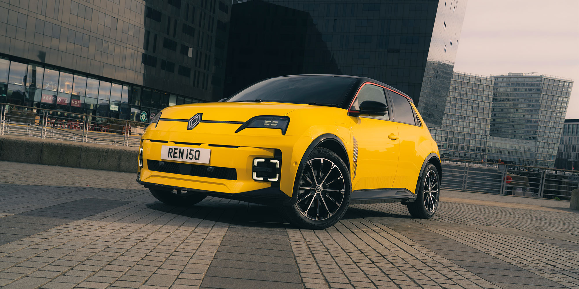 A yellow Renault 5 E-Tech Electric, parked in a city.