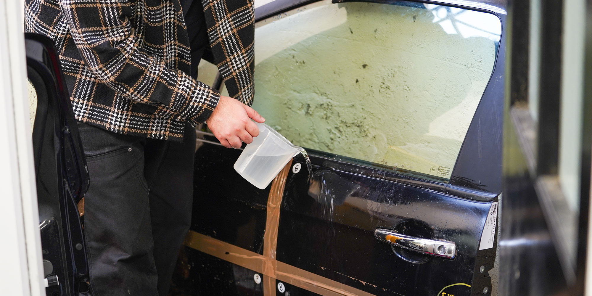 Which? cleaning expert washes away car shampoo with a jug of water.