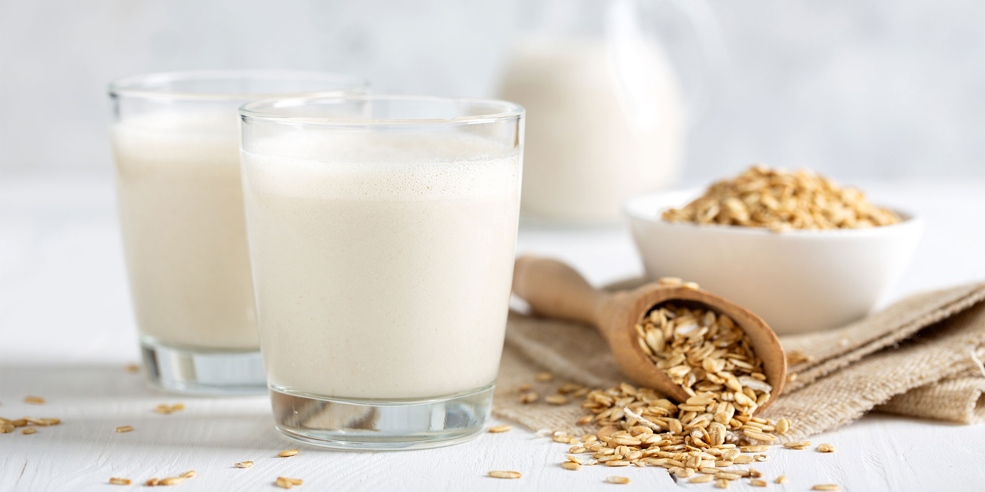 Oat milk in glasses and oat ingredients