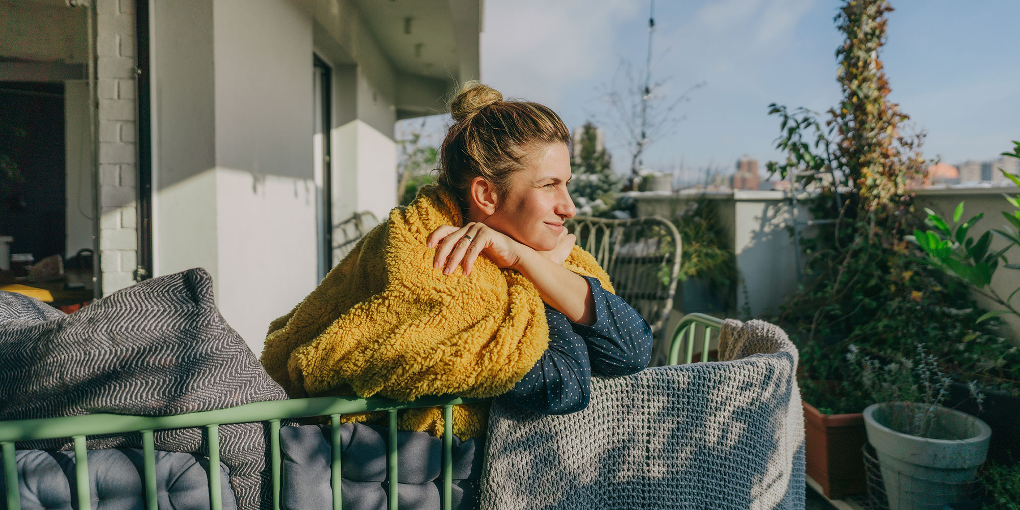 Woman basking in spring sun on balcony 