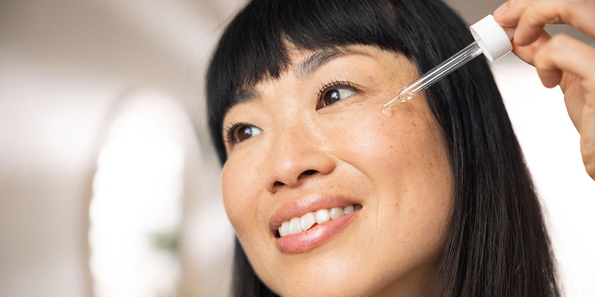 A person applying vitamin C serum to their cheek. 