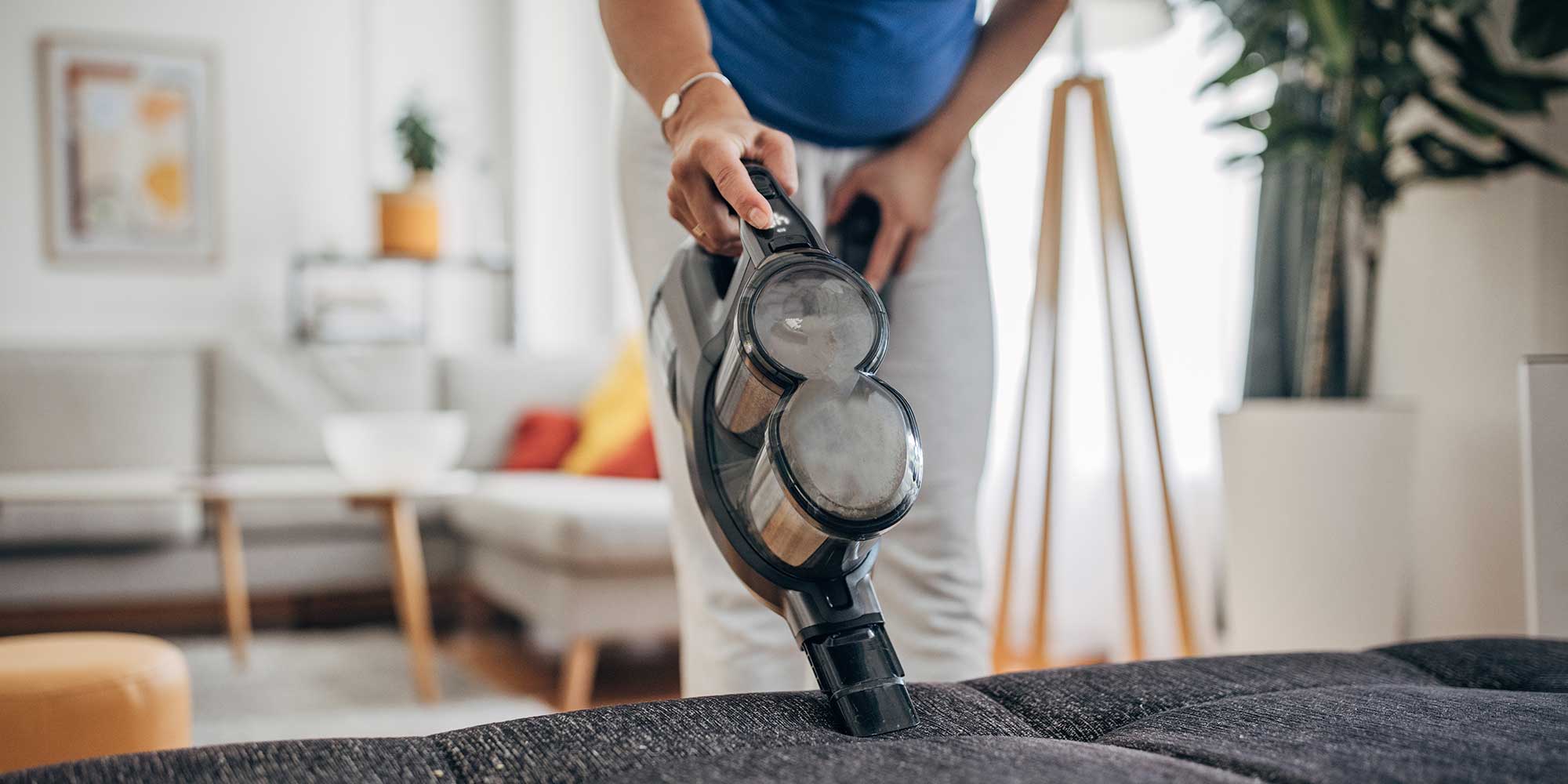 handheld vacuum cleaner being used to clean sofa