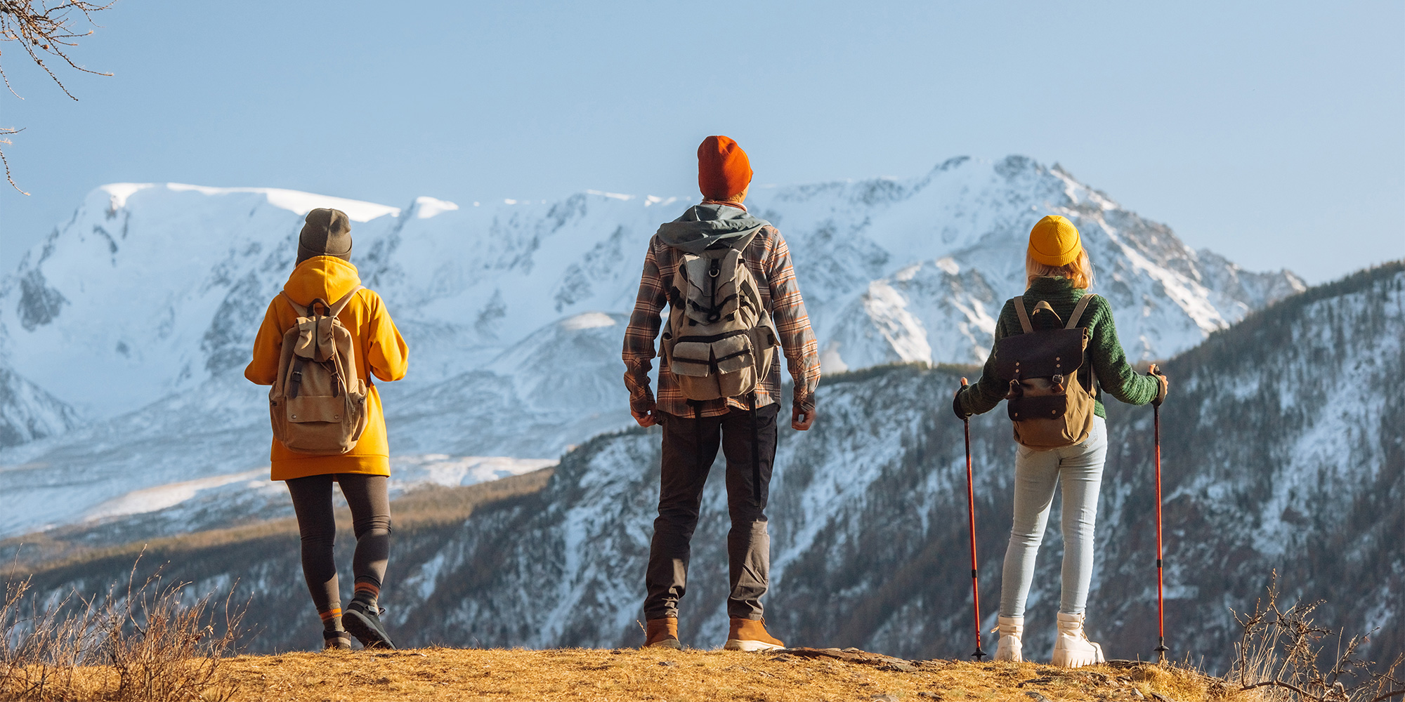 Three holidaymakers trekking through the mountains and admiring the view on their adventure/ activity holiday