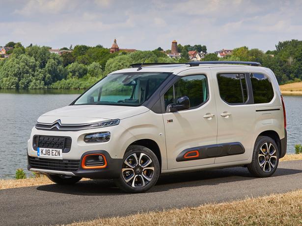 White Citroen Berlingo car on a road next to a lake