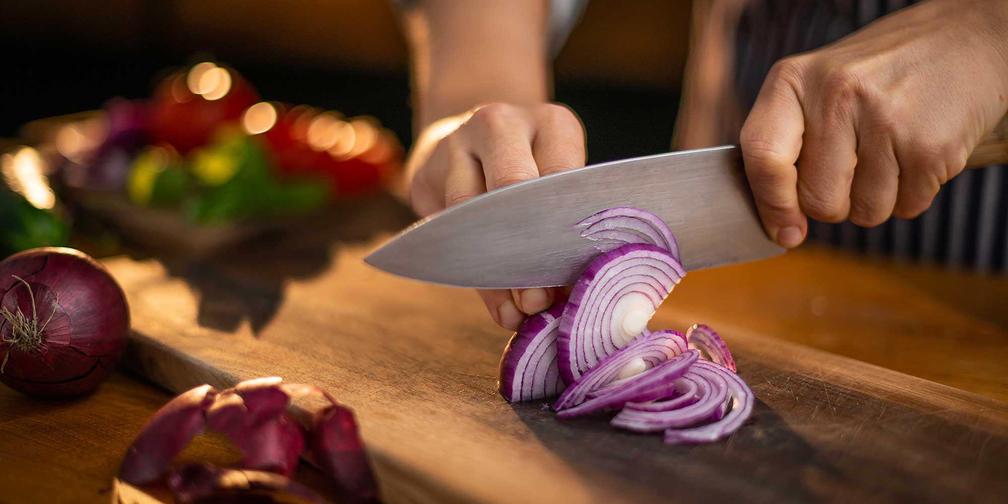 person chopping up a red onion with a kitchen knife