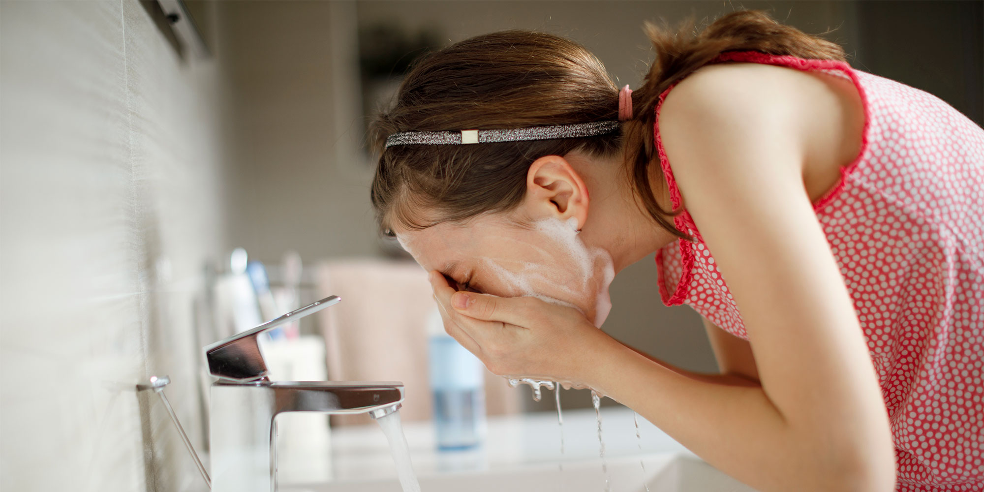 person washing their face at a sink