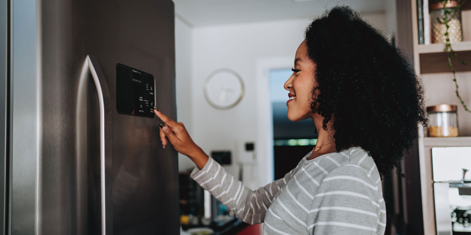Smiling woman taps touchscreen on her fridge