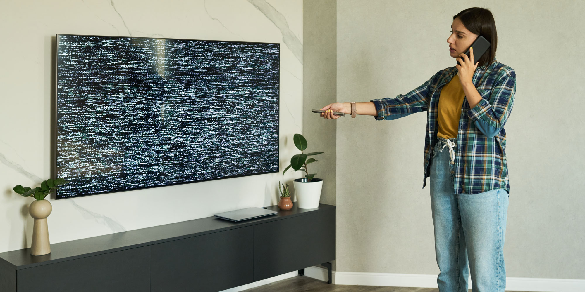 A woman with is trying to fix her TV which isn't displaying a picture