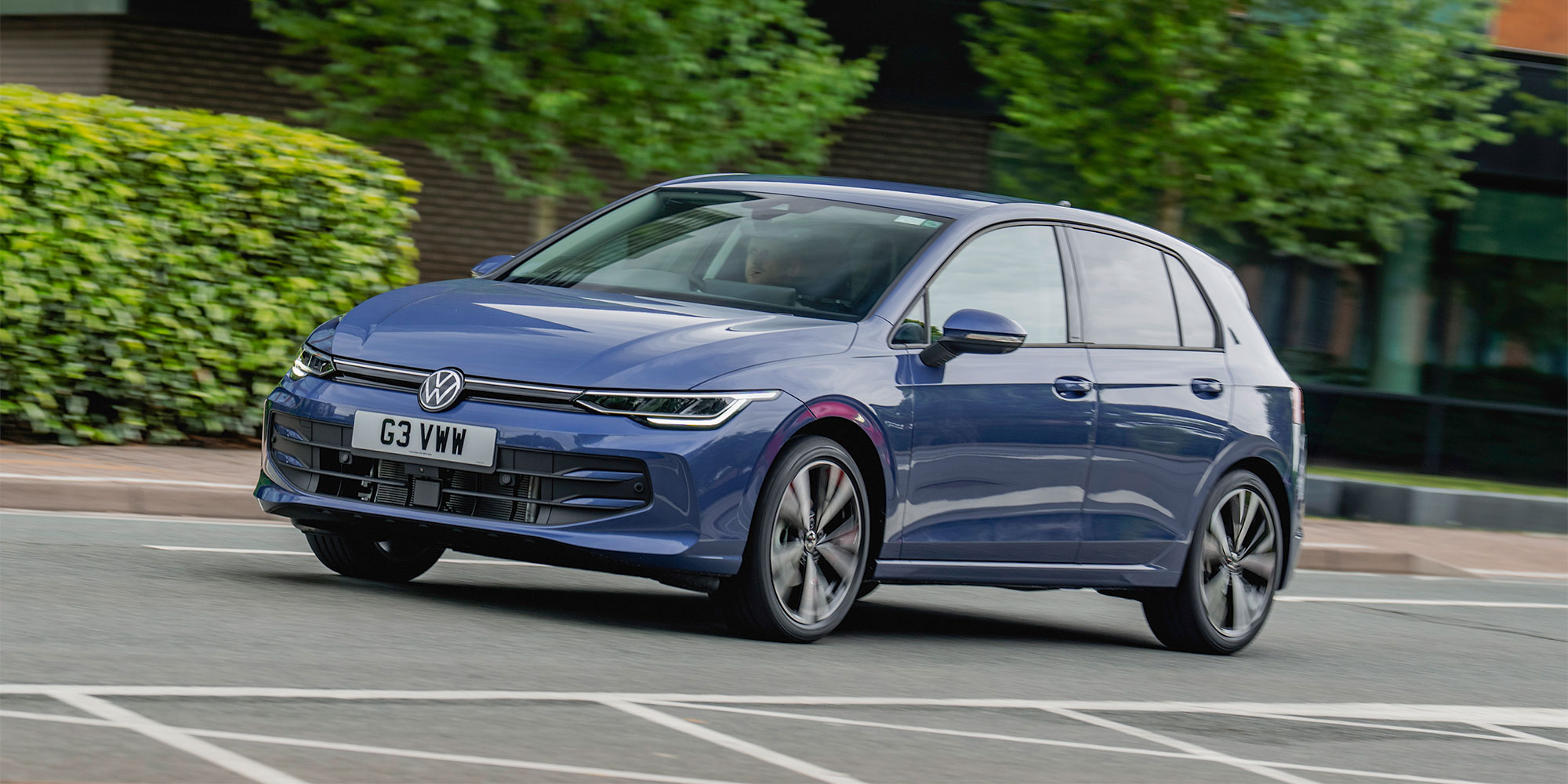 Blue Volkswagen Golf car with number plate G3 VWW driving on a road with trees and bushes.