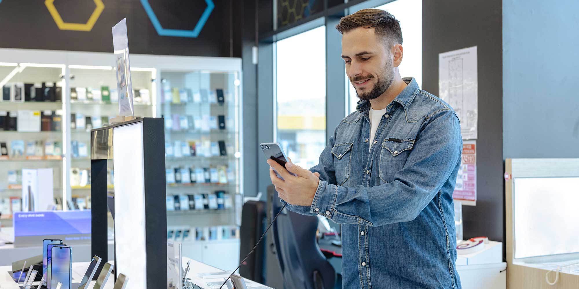 a man looking at a phone in a tech store