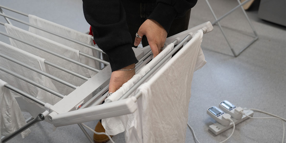 Our tester fitting medium sized T-shirts onto a heated airer to test drying speed