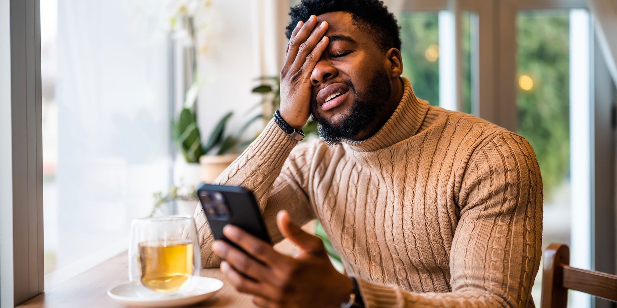 Stressed man holding his phone in one hand and his head in the other
