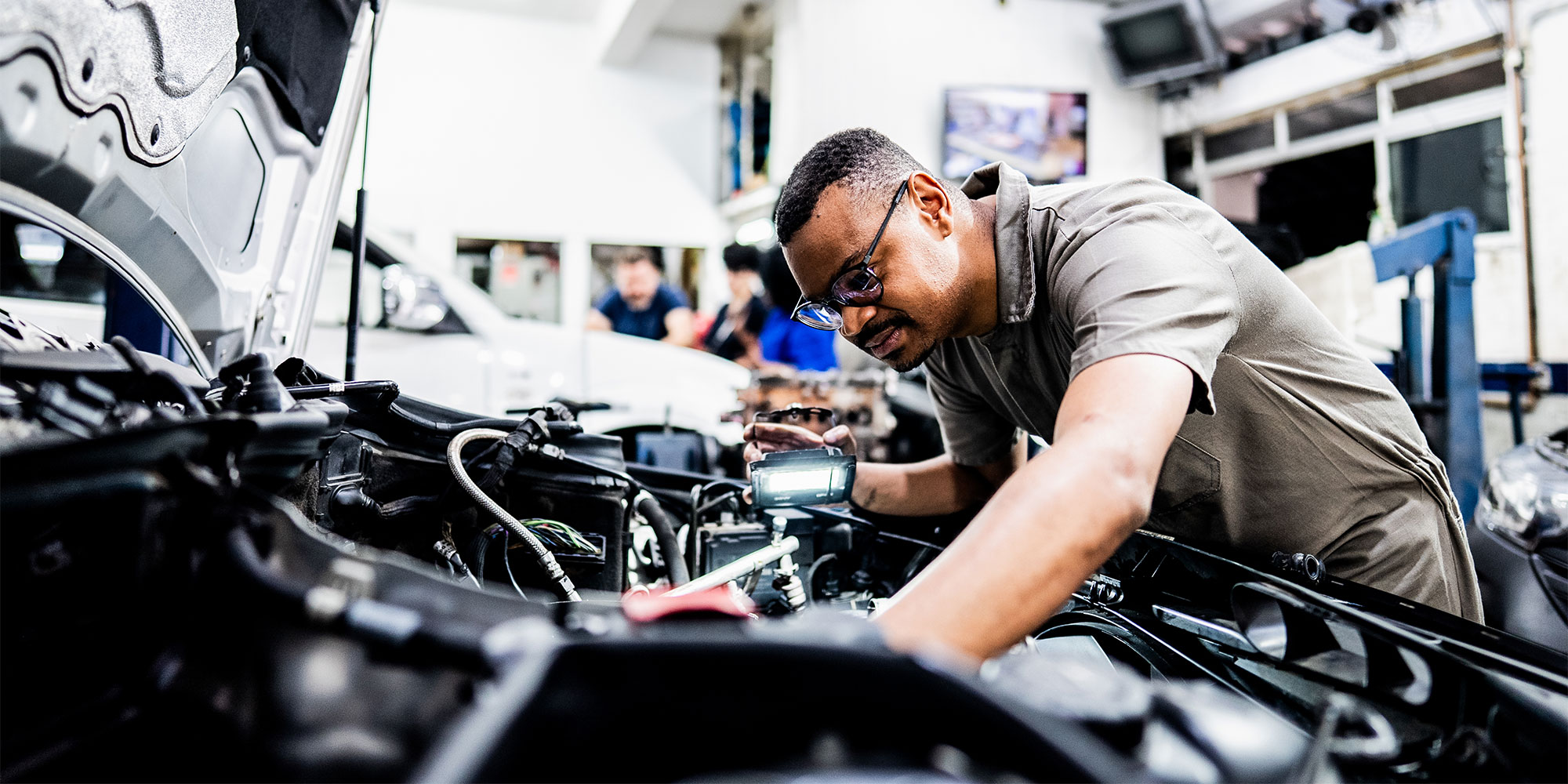 A mechanic working on a car, under the bonnet