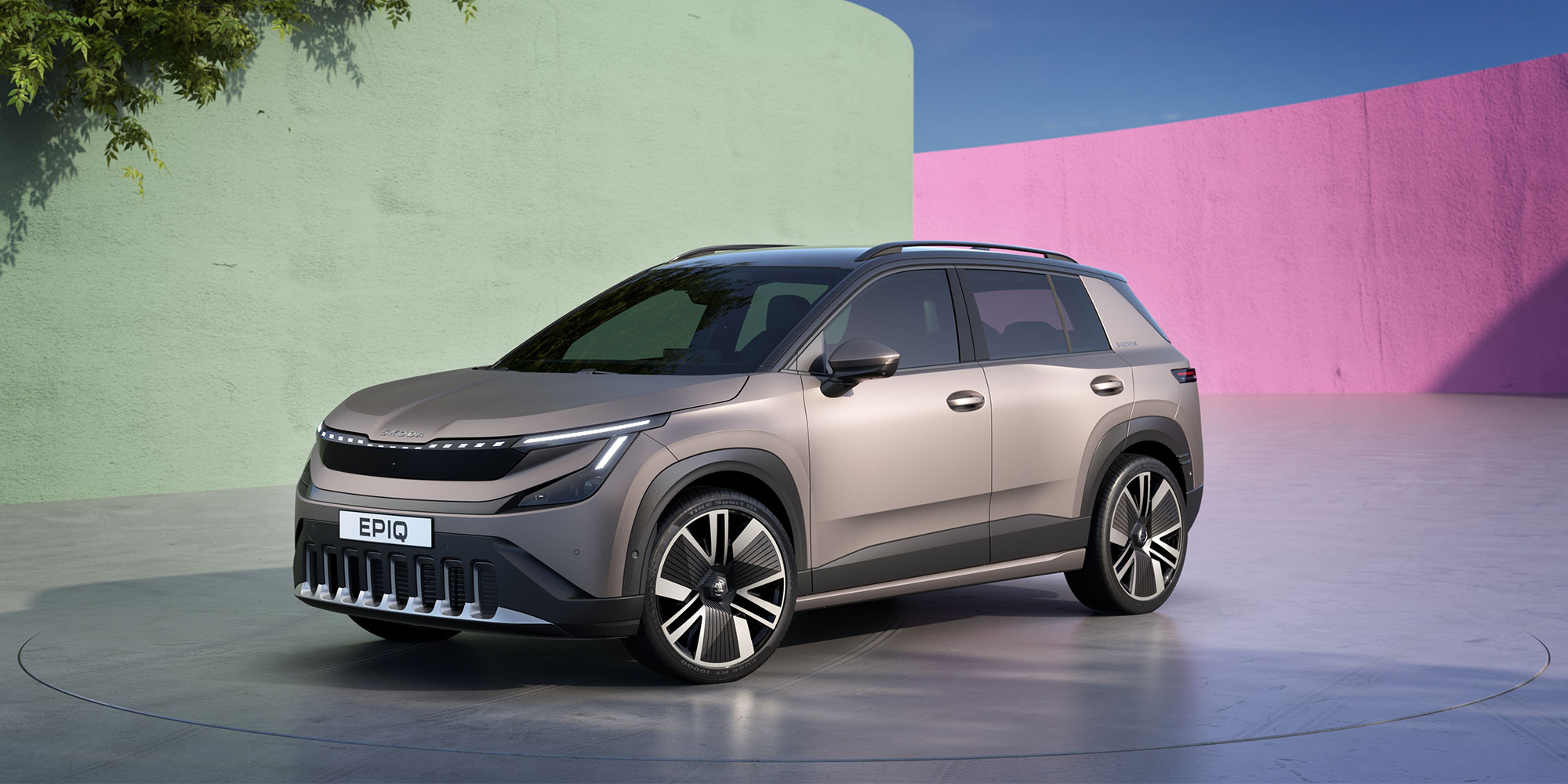 A grey Skoda Epiq, parked against a multicoloured background