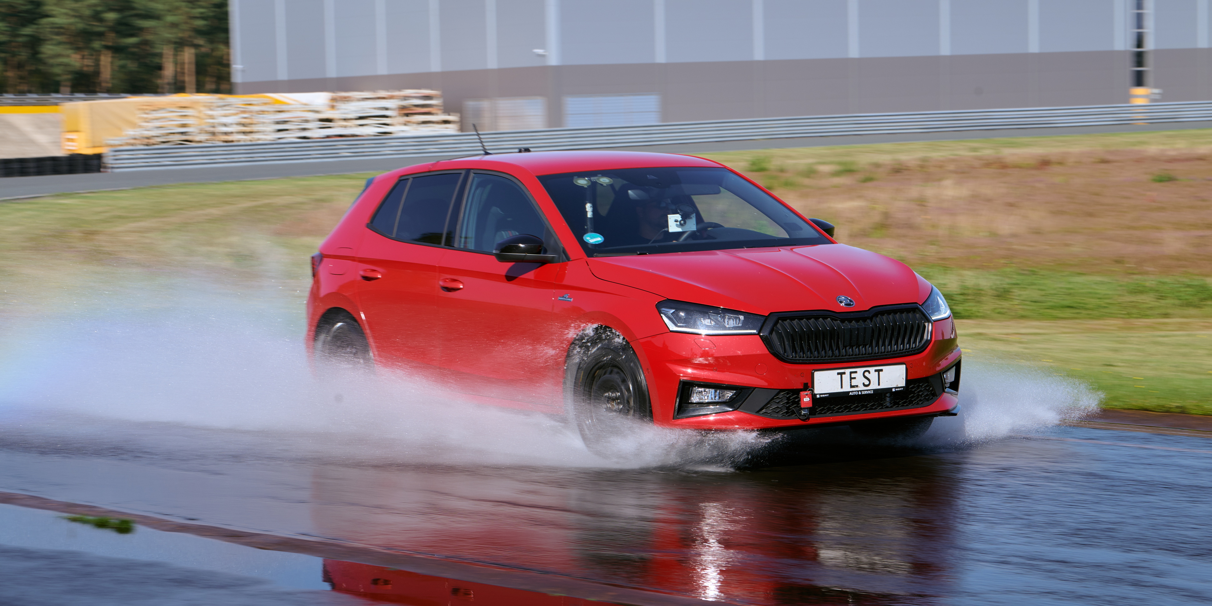 Red car on wet road during tyre test
