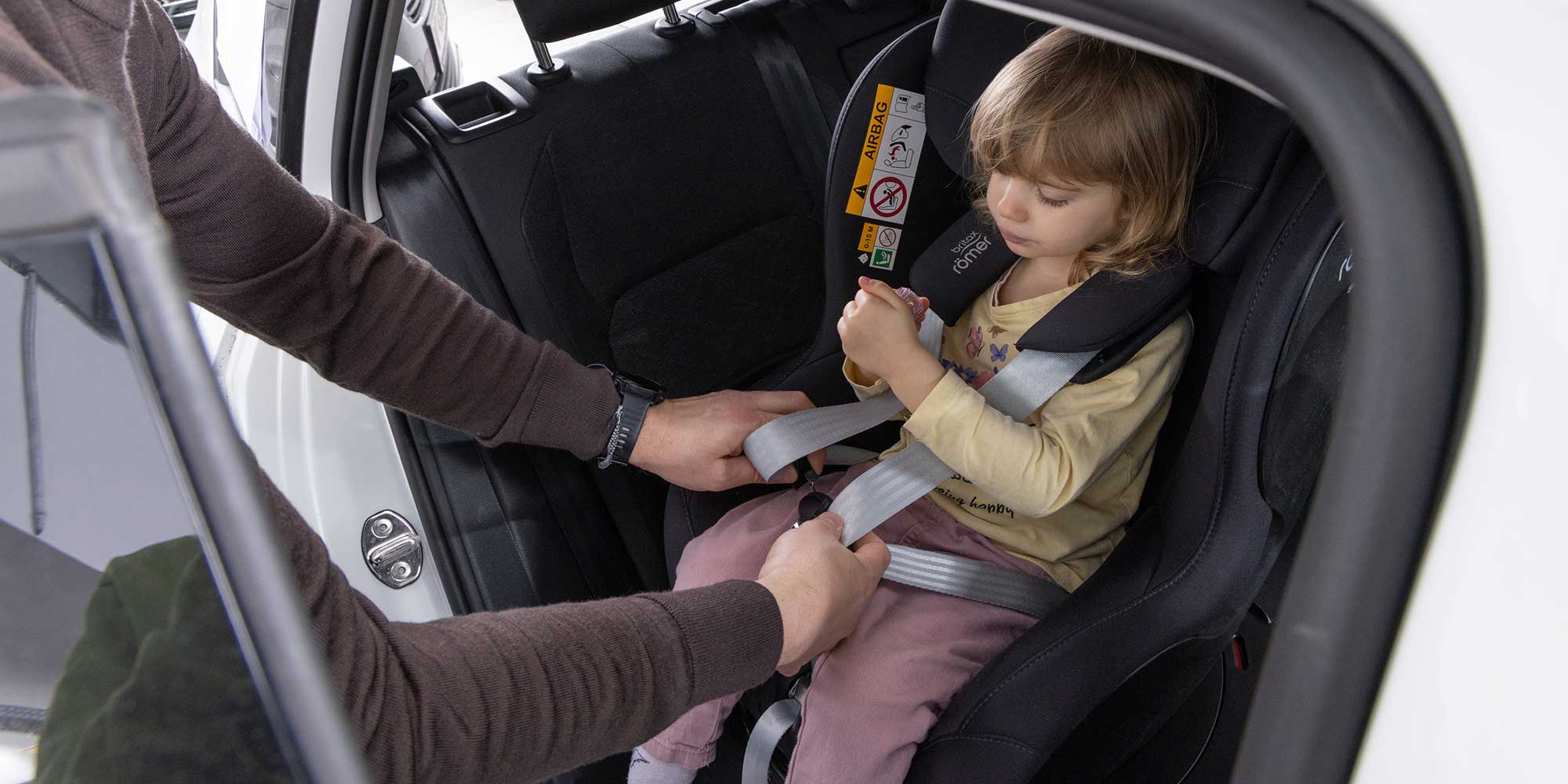 Child being strapped into a rotating swivel car seat