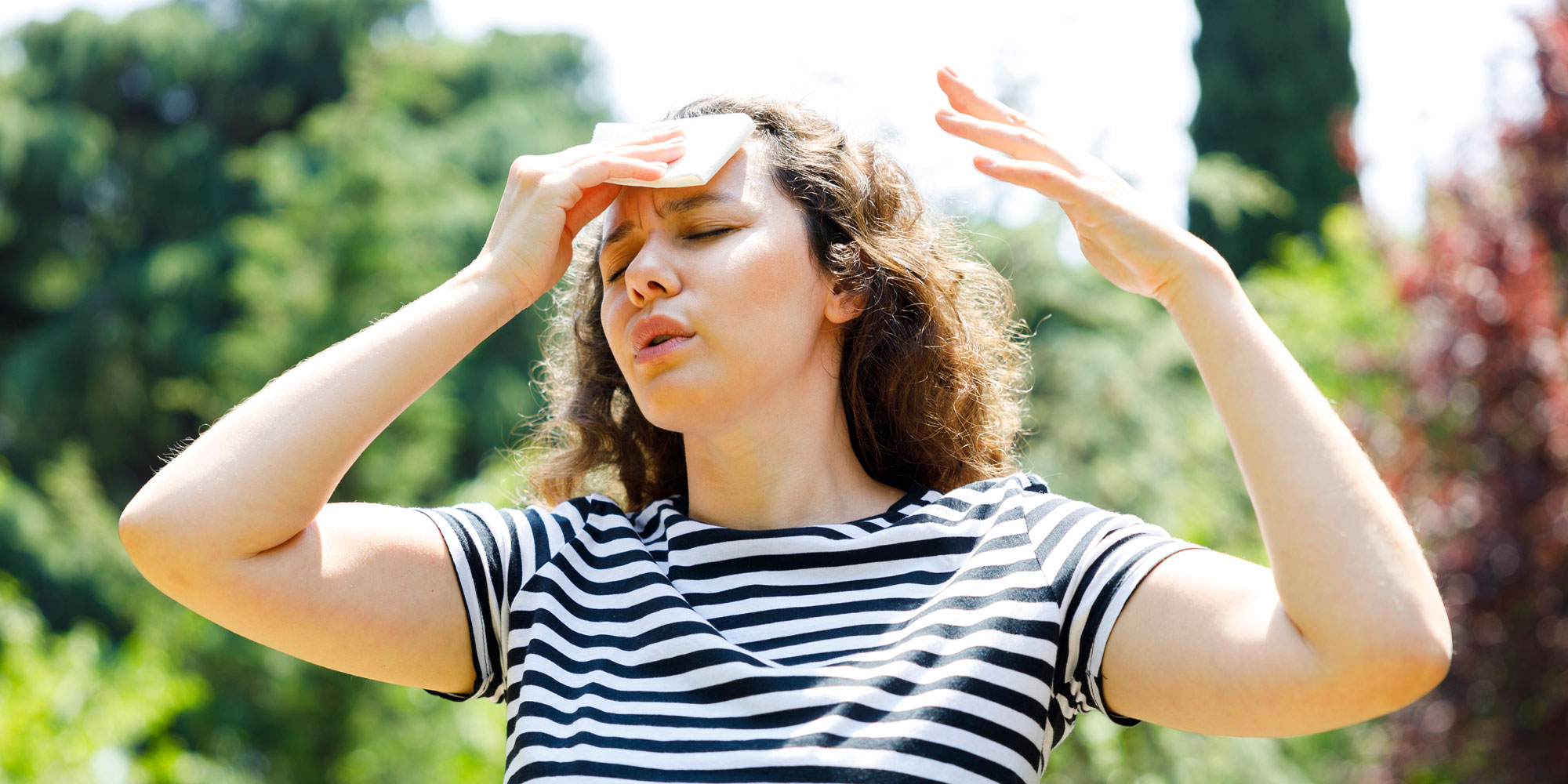 A woman wiping sweat off of her forehead