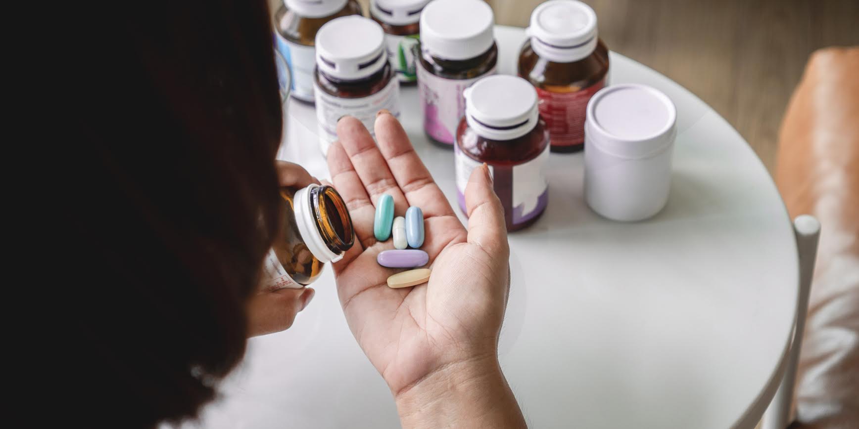 A woman holding several pills in her hand