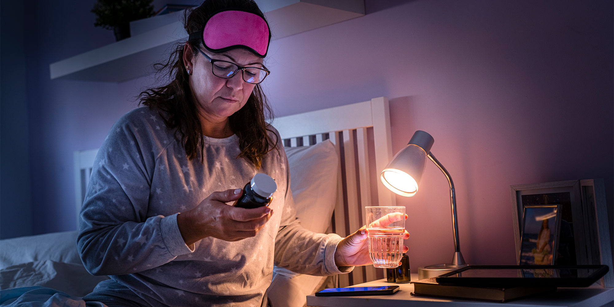 A woman examining the label on a bottle before sleeping at night