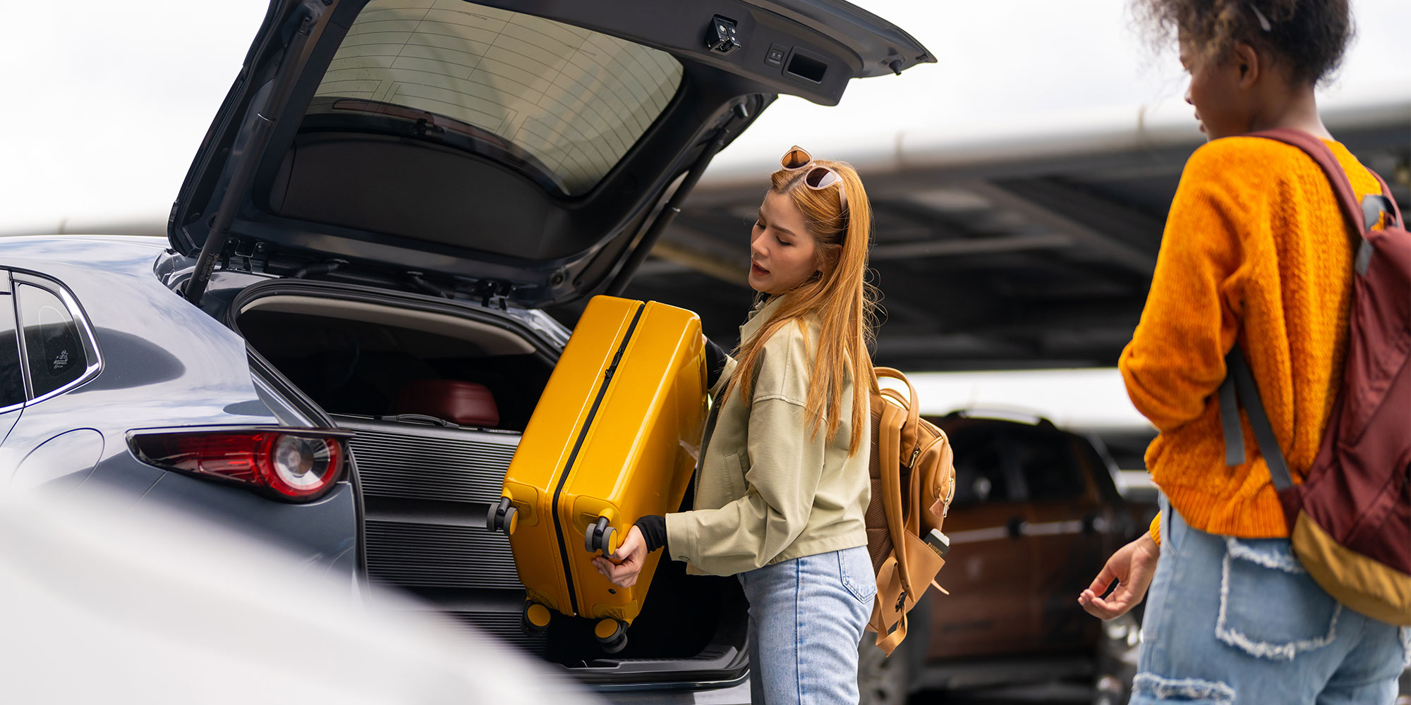 Woman lifting suitcase out of car boot