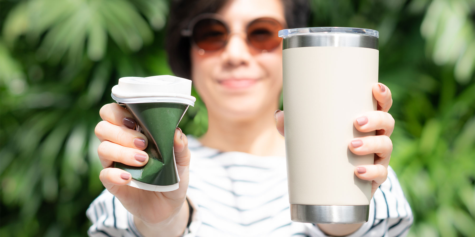 Woman holding a reusable and disposable coffee cup