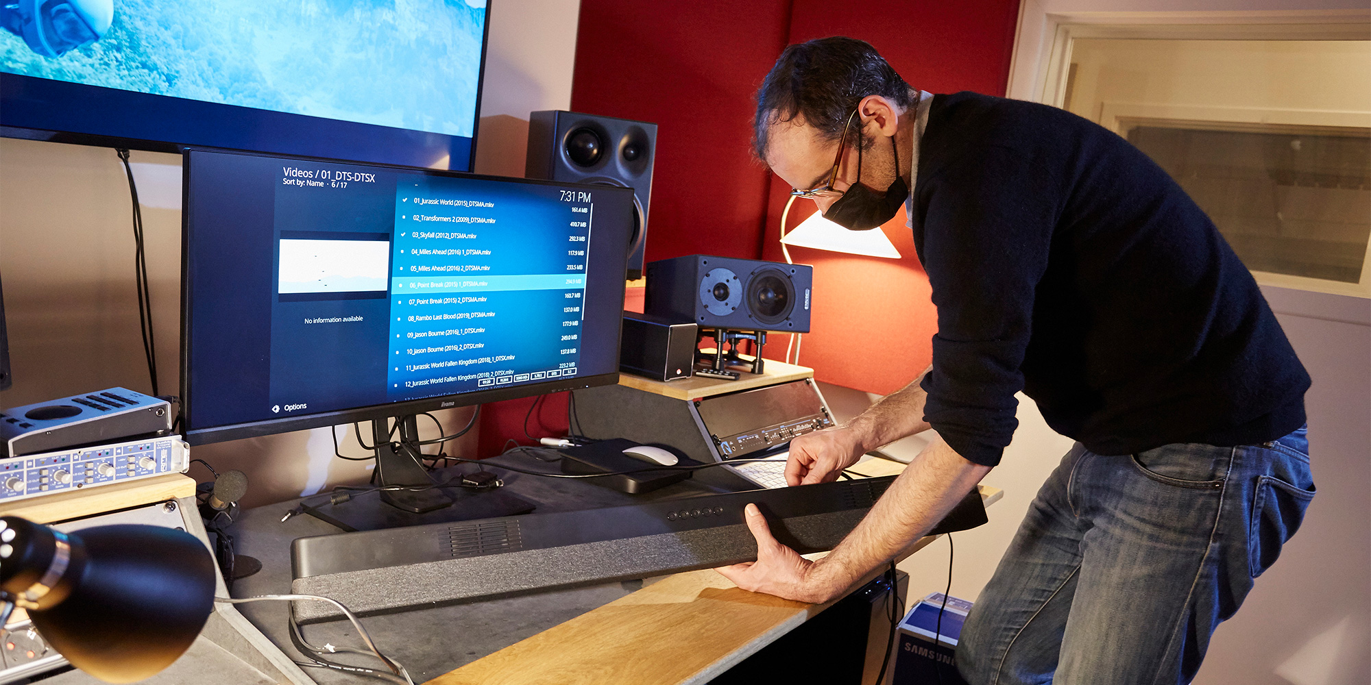 Man adjusting soundbar equipment in a studio.