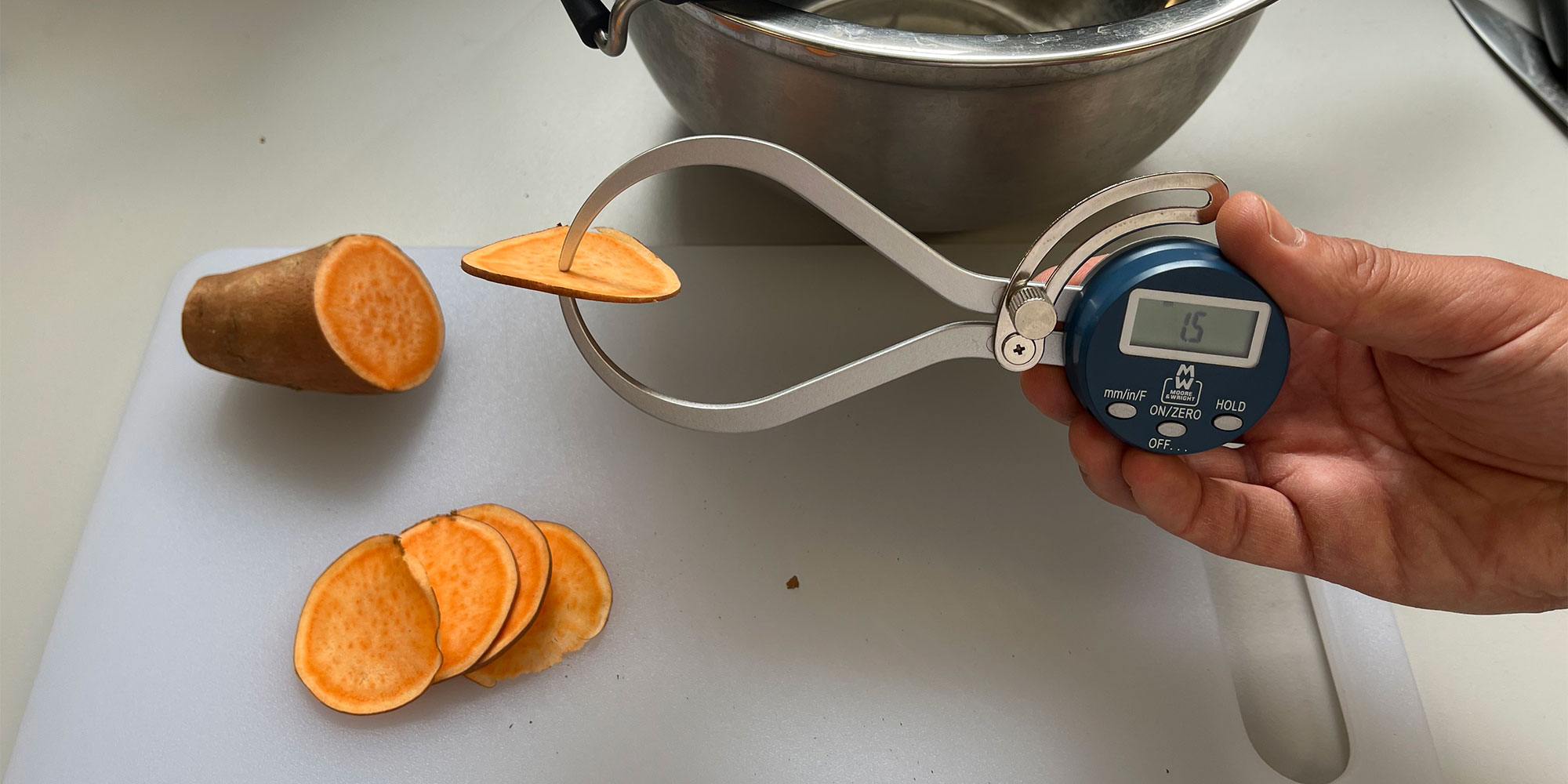 Our expert tester measures the thickness of slices of sweet potato using a digital thickness gauge