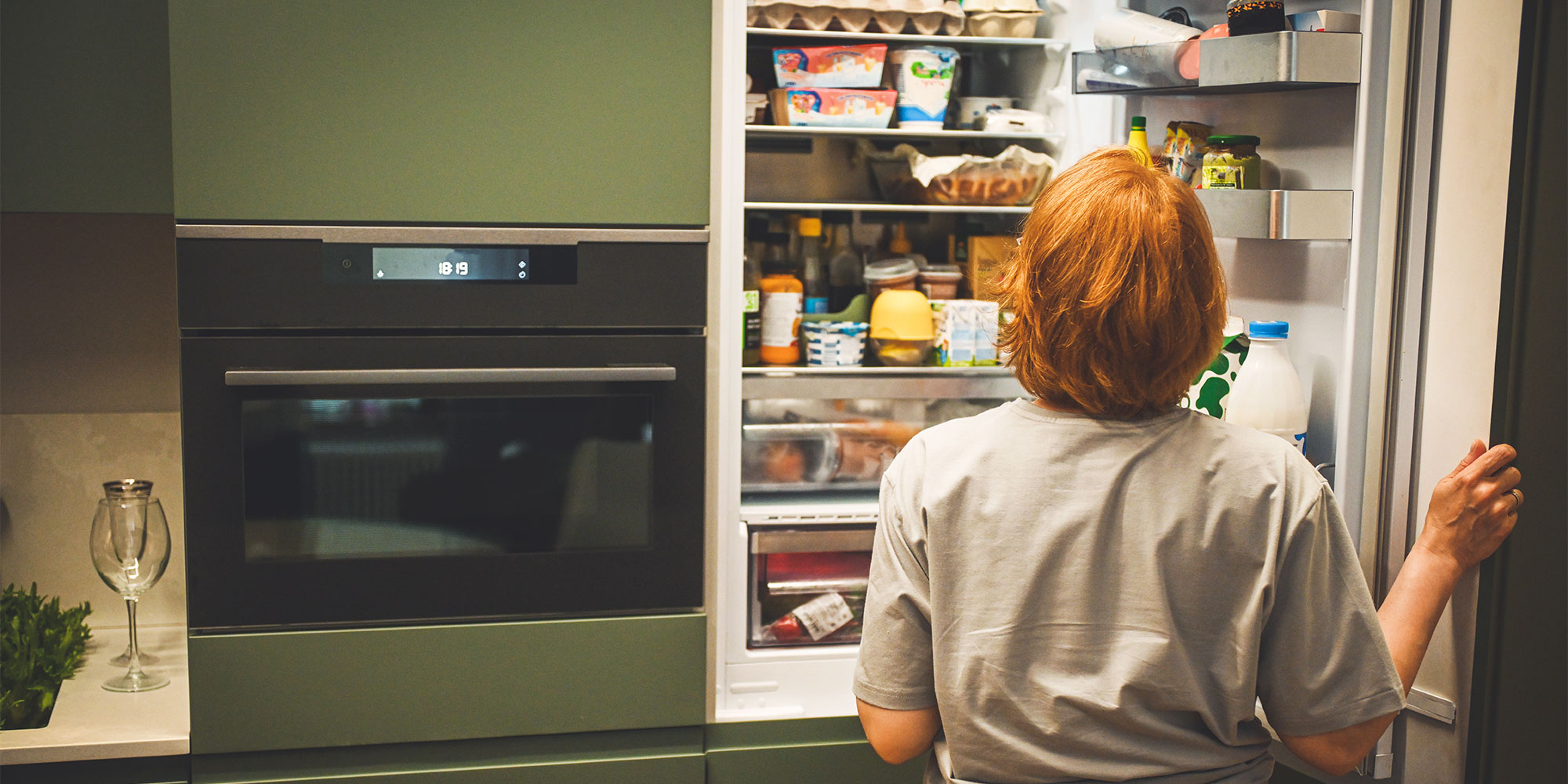 Woman staring into overfilled fridge