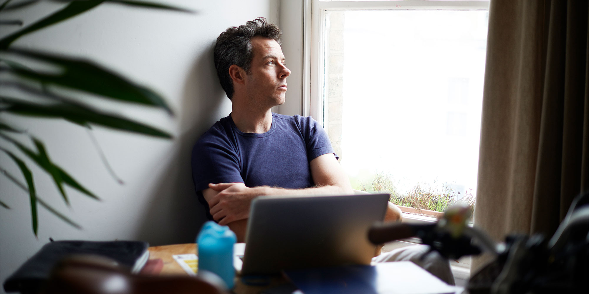Pensive man at laptop looking out of the window
