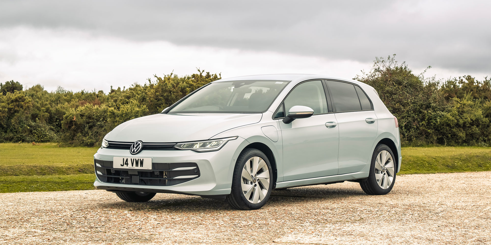 A blue Volkswagen Golf eHybrid, parked on gravel.