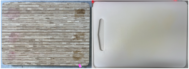 Wooden and plastic chopping board side by side. The wooden board has purple beetroot and oil staining. The plastic board has orange carrot staining. 