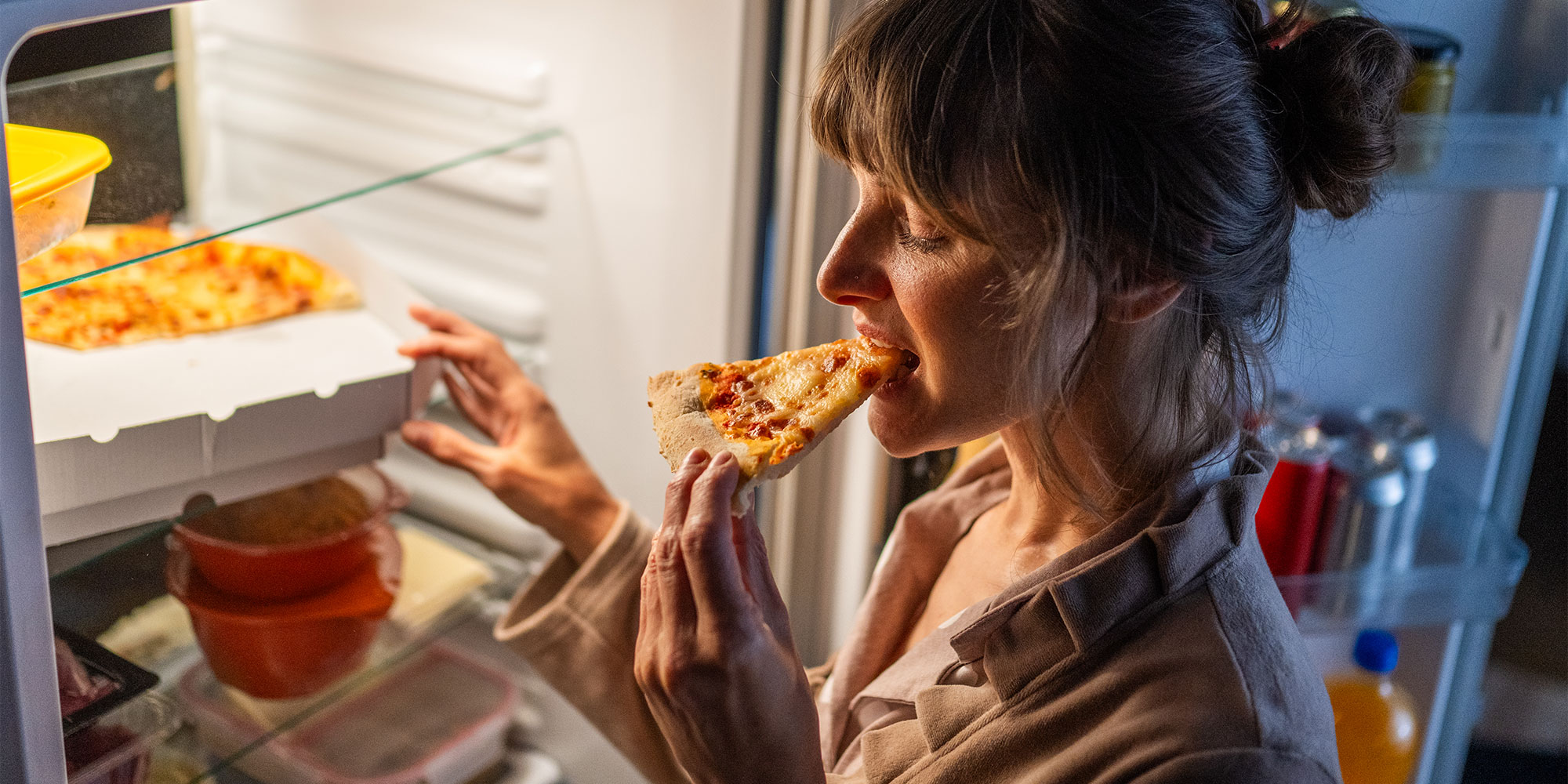 women eating pizza from the fridge late night snacking