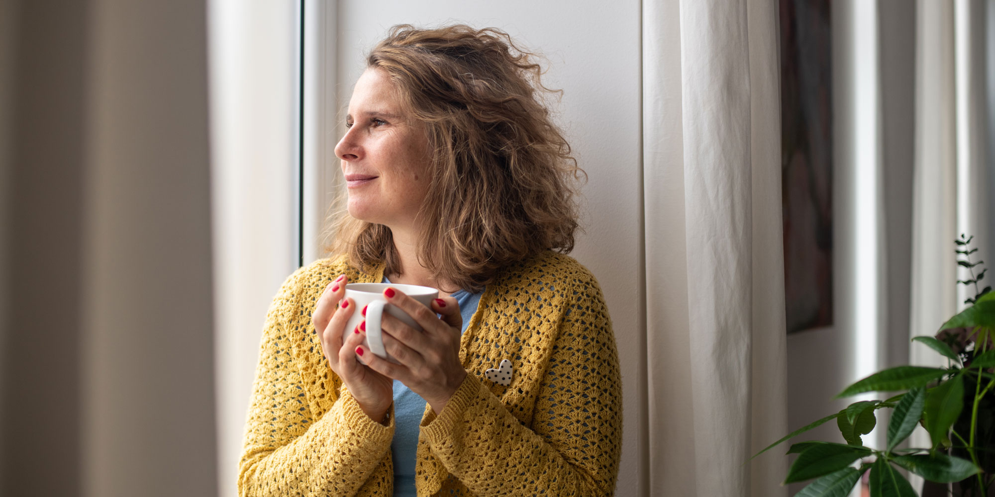 A woman by a window, looking out into the daylight