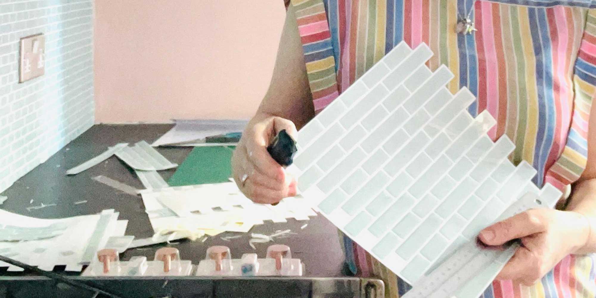 Martha Roberts, Which? senior researcher and writer, cutting her stick-on kitchen tiles to the desired size