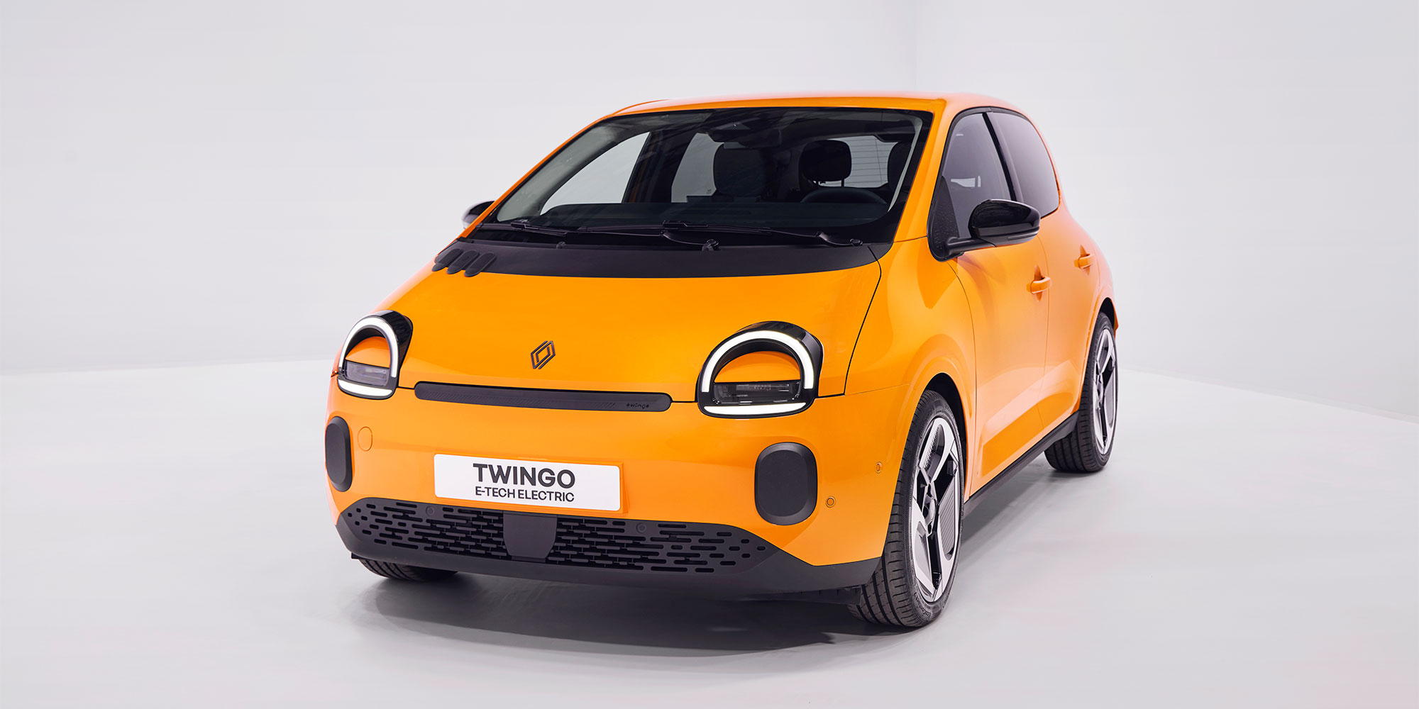 An orange Renault Twingo EV, parked against a white background
