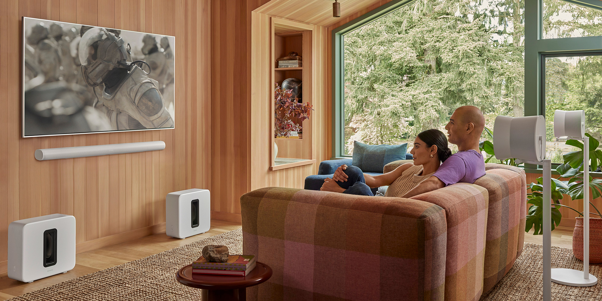 Couple watch TV on their sofa with a Sonos Arc Ultra soundbar and Sub 4