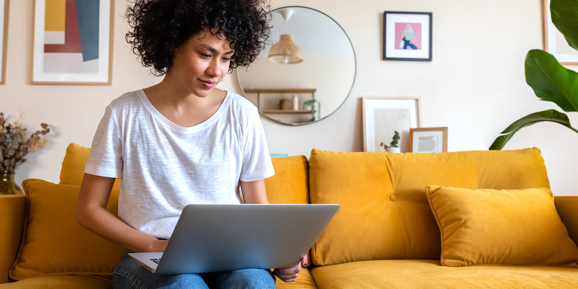Woman sitting on a sofa looking at a laptop to check a guarantee