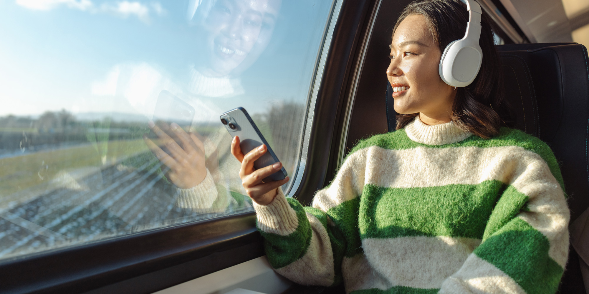 A woman wearing headphones while on a train