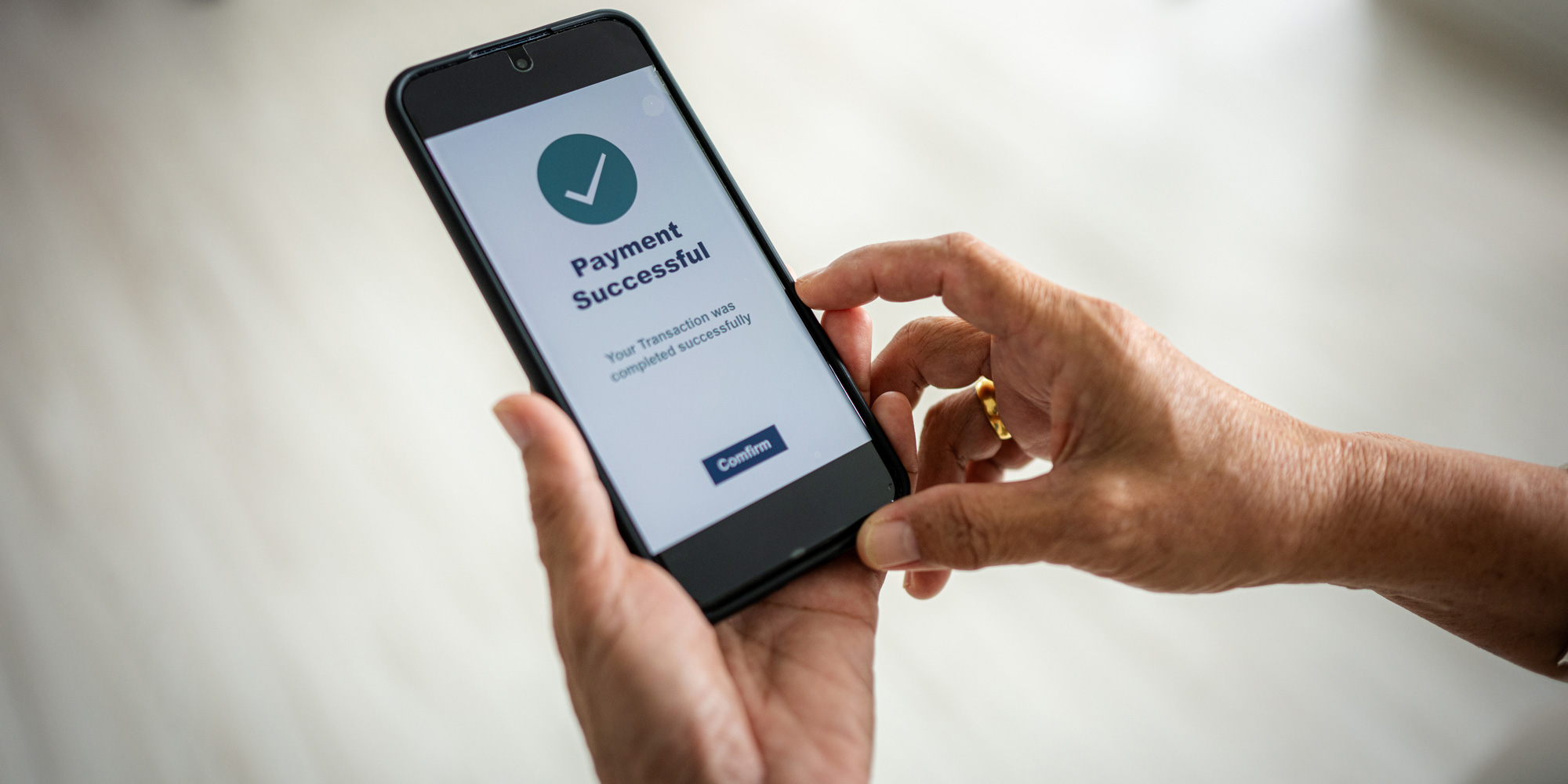 Hand holding mobile phone showing 'payment successful'