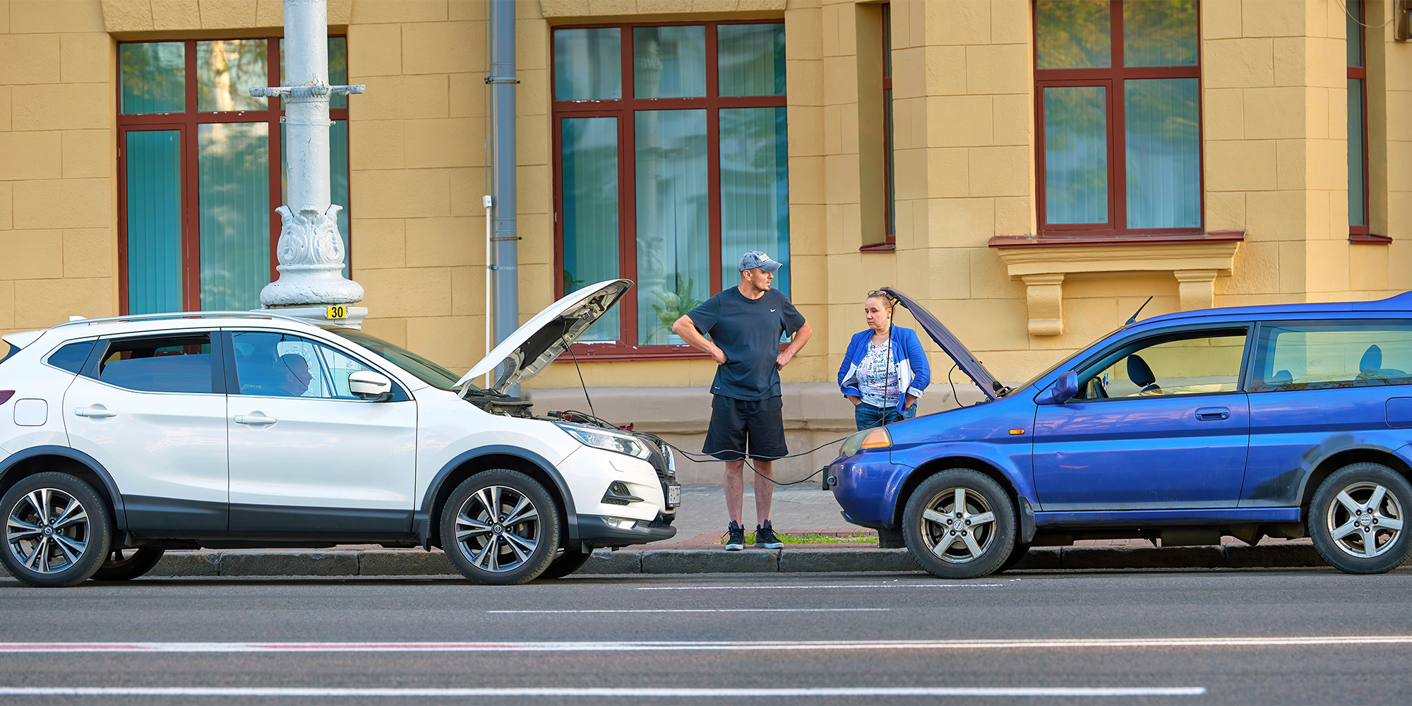 Two SUVs jump starting on the side of the road.