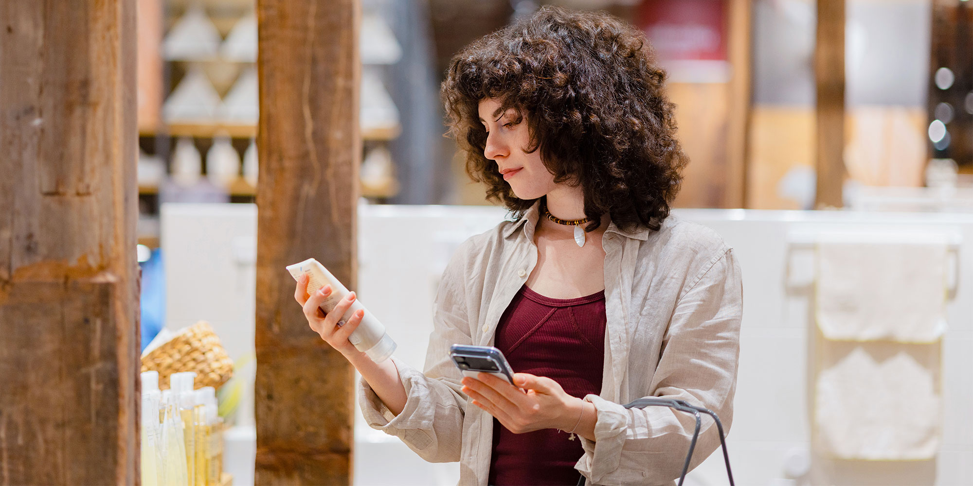 A person reading the ingredients on a skincare product and comparing it to the information on their phone. 
