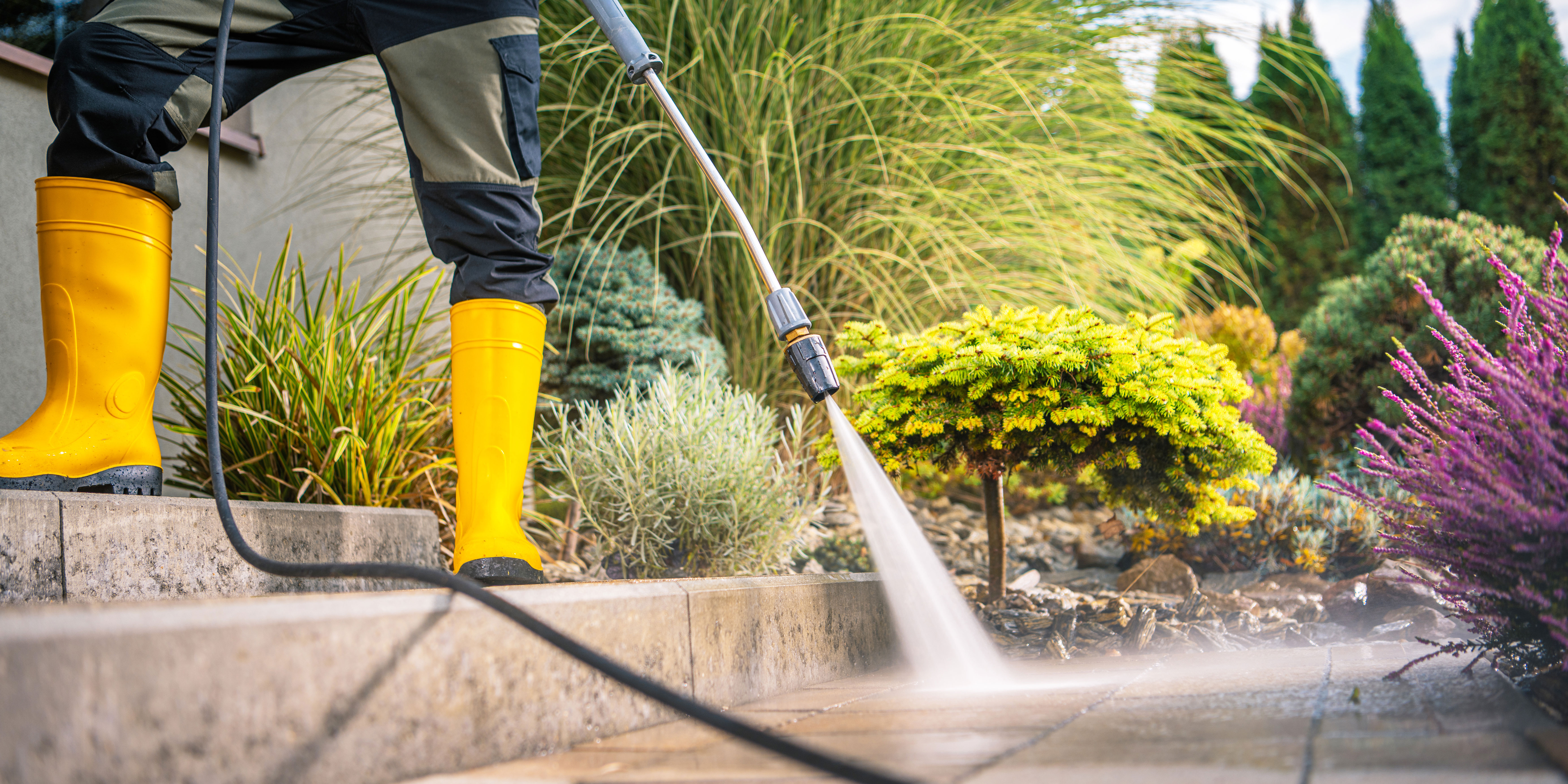somebody using a pressure washer to clean a patio