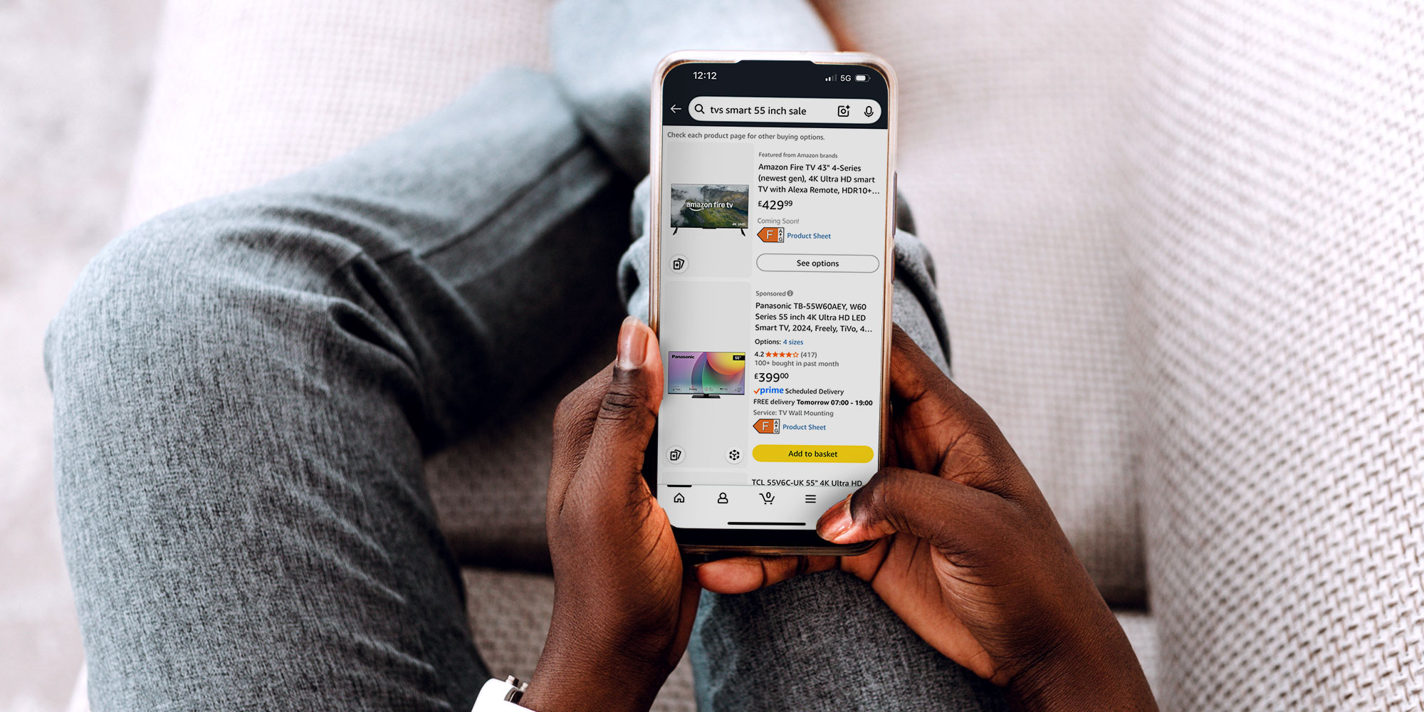 Someone on a sofa shopping for a TV online on their phone