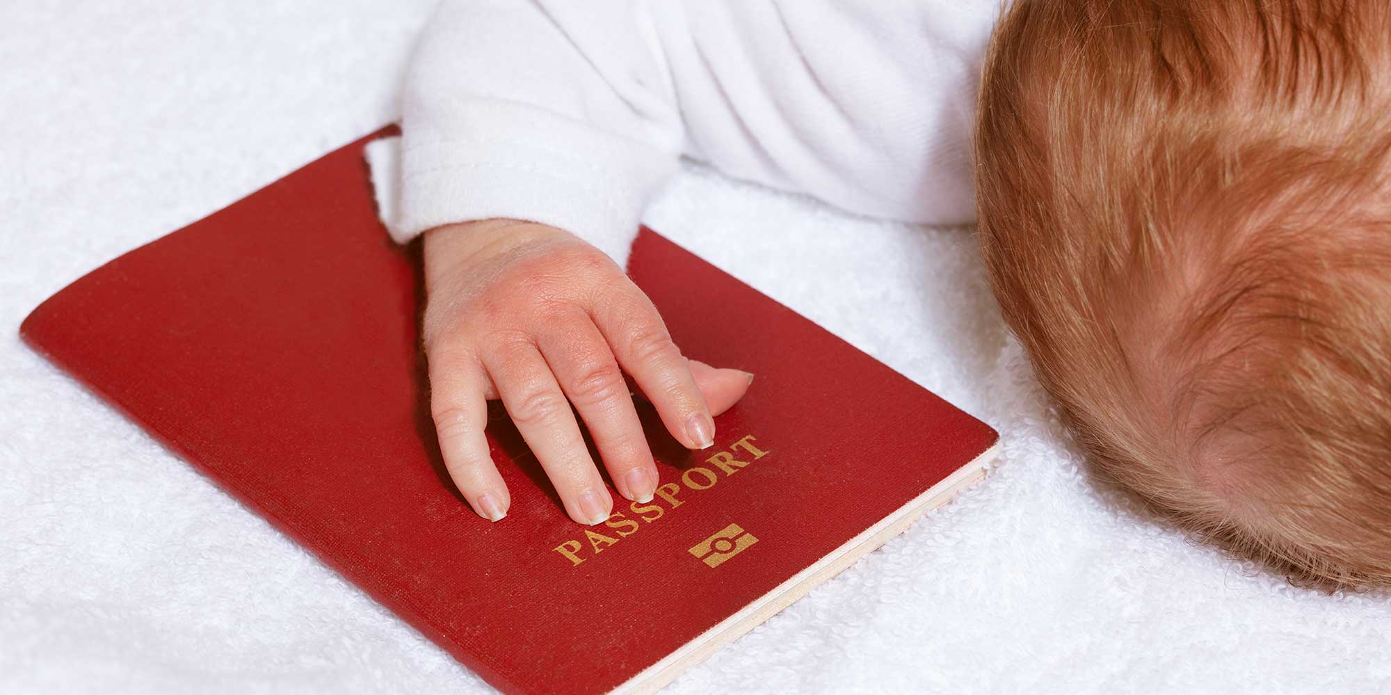 A baby's hand on a red passport