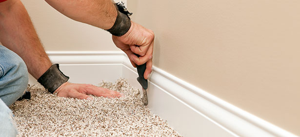 A close up of someone's hands fitting a carpet