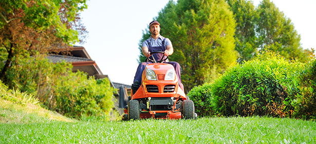 Man driving an orange ride-on lawn mower