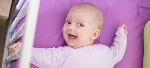 Baby smiling while lying in cot