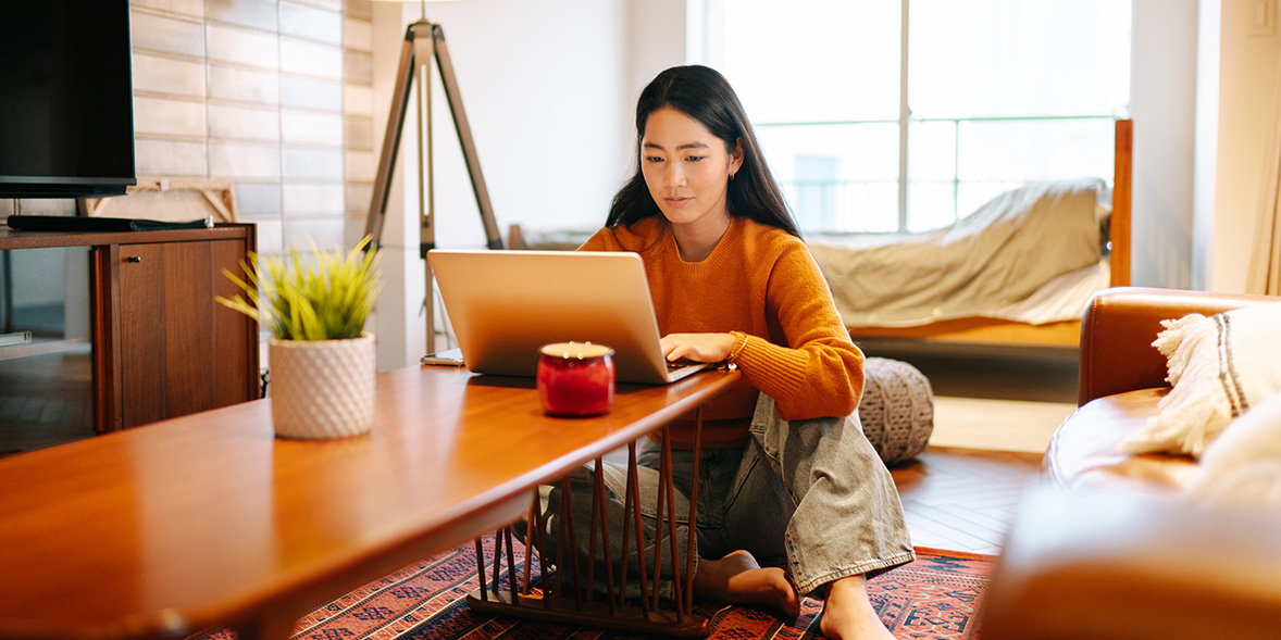 Woman sitting on the floor at home typing on her laptop