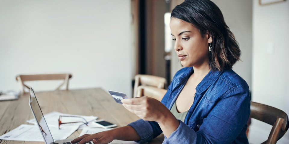 Woman at a computer holding a credit card