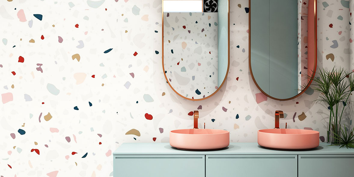 Bathroom wallpaper with a white background and different shapes of colour on a bathroom wall with two pink sinks and a pale green bathroom vanity unit
